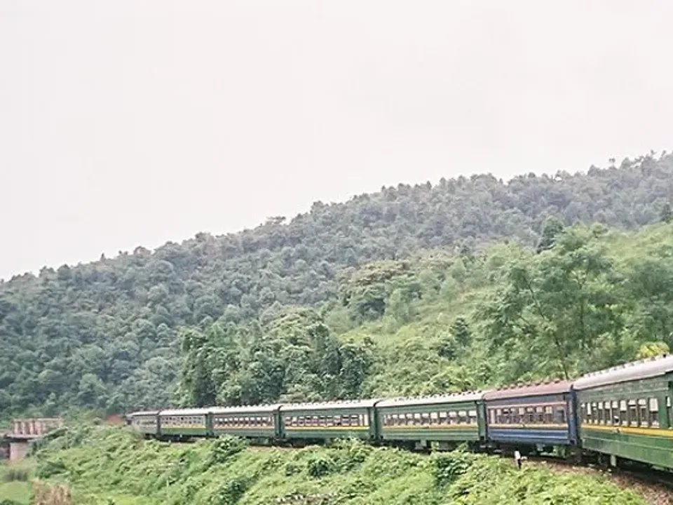 A passenger train winding through green hills in Vietnam
