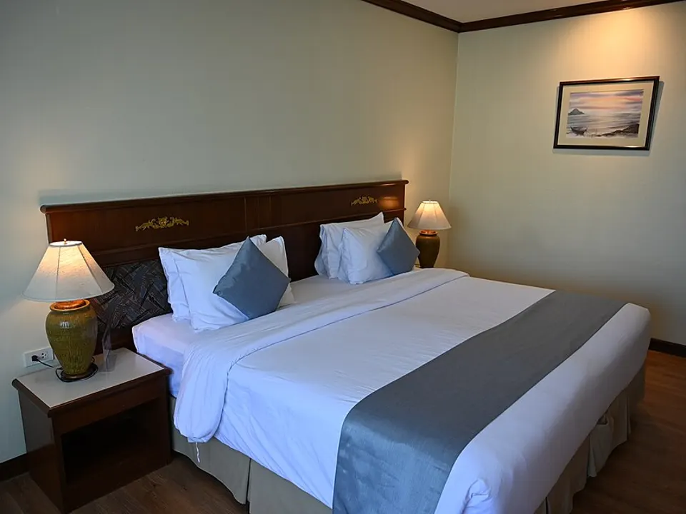 A neatly made king bed in a hotel room with bedside lamps