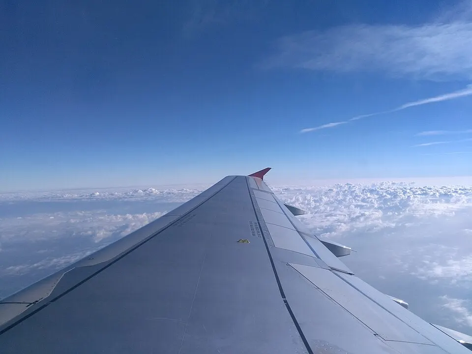 An aircraft wing above white clouds