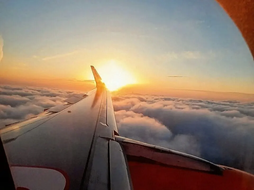 Sunset over the clouds seen through an aircraft window